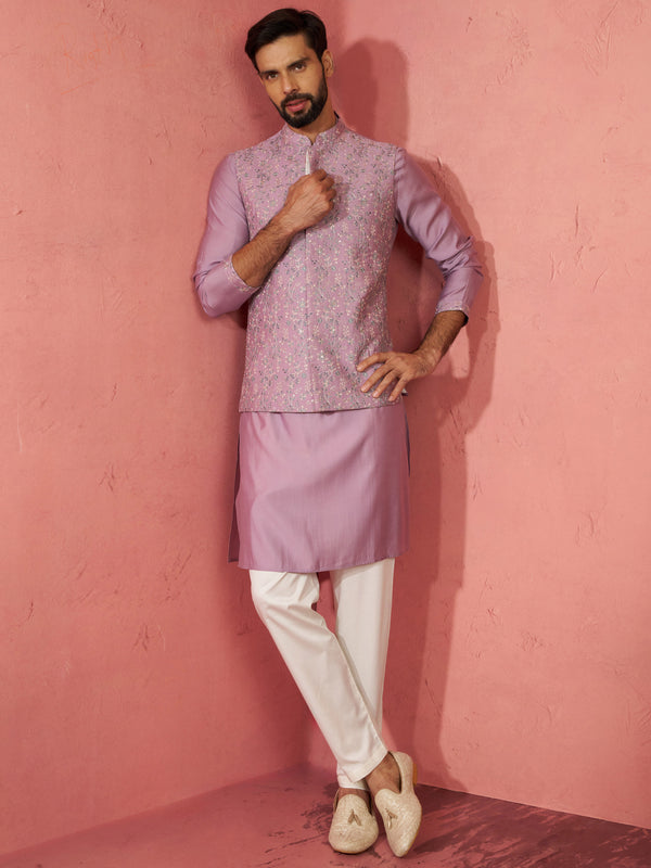 Man wearing a light purple traditional outfit against a pink wall