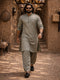 Man in traditional attire walking through a rustic alleyway.