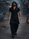 Man in black outfit walking through a dark, possibly post-apocalyptic setting.