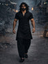 Man in black outfit walking through a dark, possibly post-apocalyptic setting.