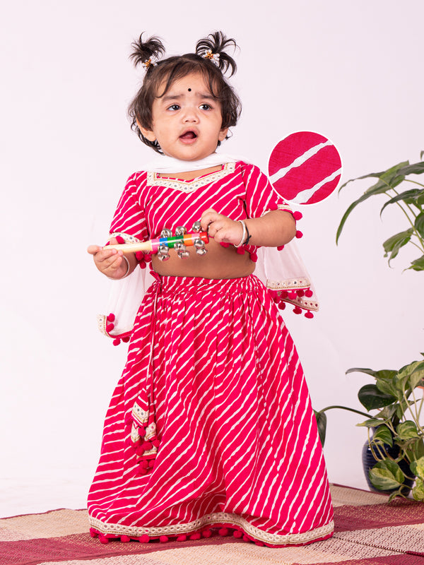 A young girl wearing a traditional pink lehenga choli with dupatta, featuring a sweetheart neck and pom pom lace detailings.