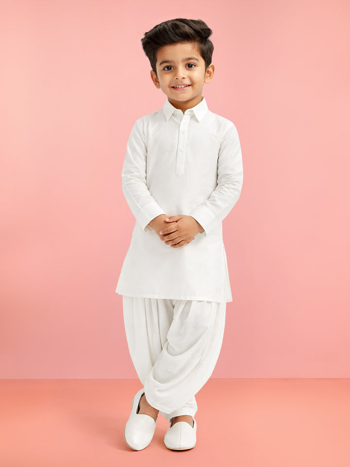 Child wearing a white traditional outfit against a pink background